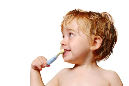 A happy young boy brushes his teeth